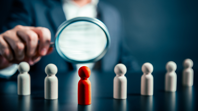 Magnifying glass focused on a highlighted figure among a team